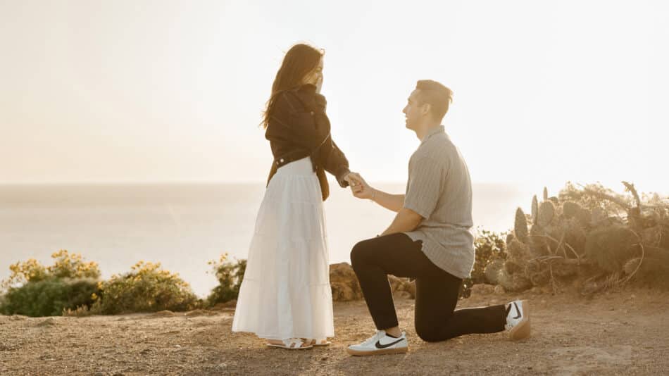 Man proposing on one knee during sunset proposal at Point Dume in Malibu