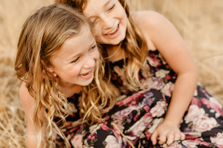 Malibu family photography sisters laughing together in golden field at sunset