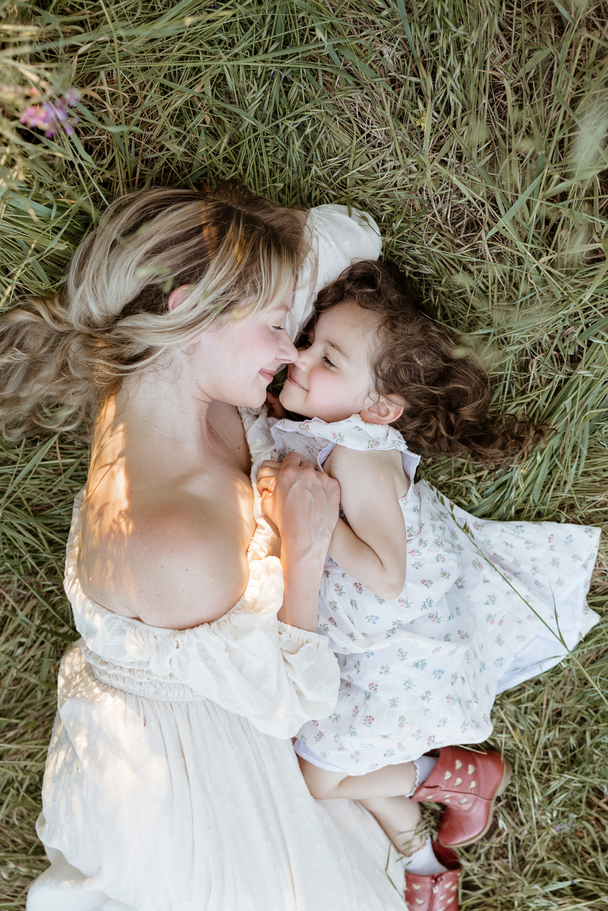 Calabasas family photography mother and daughter lying in grass embracing in soft natural light