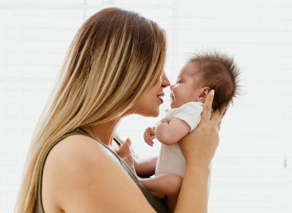 Mother holding newborn baby close to her face during natural light in-home newborn photography session