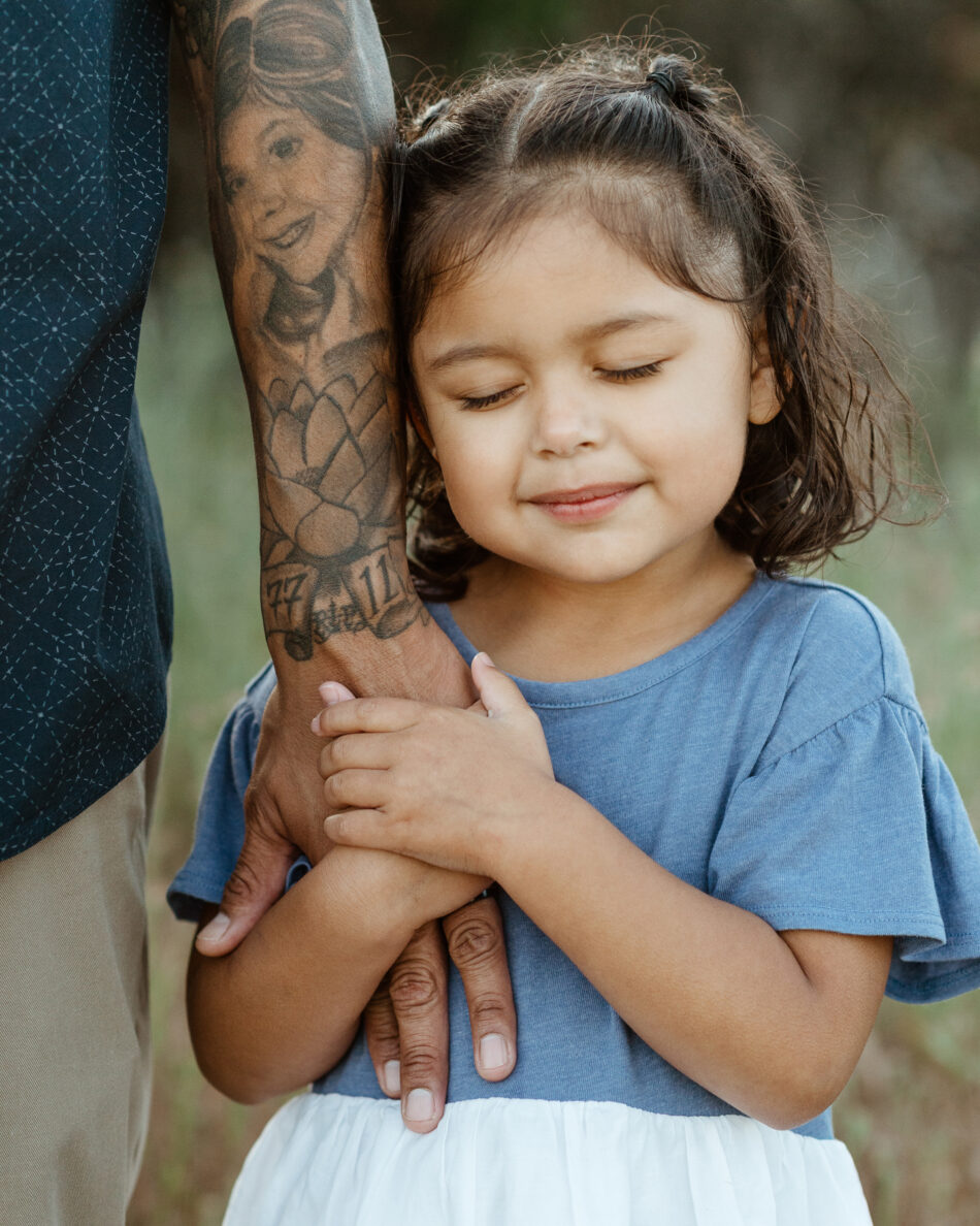 Little girl holding her father’s arm during a family photography session at Wildwood Park in Thousand Oaks photographed by Erica Montgomery.