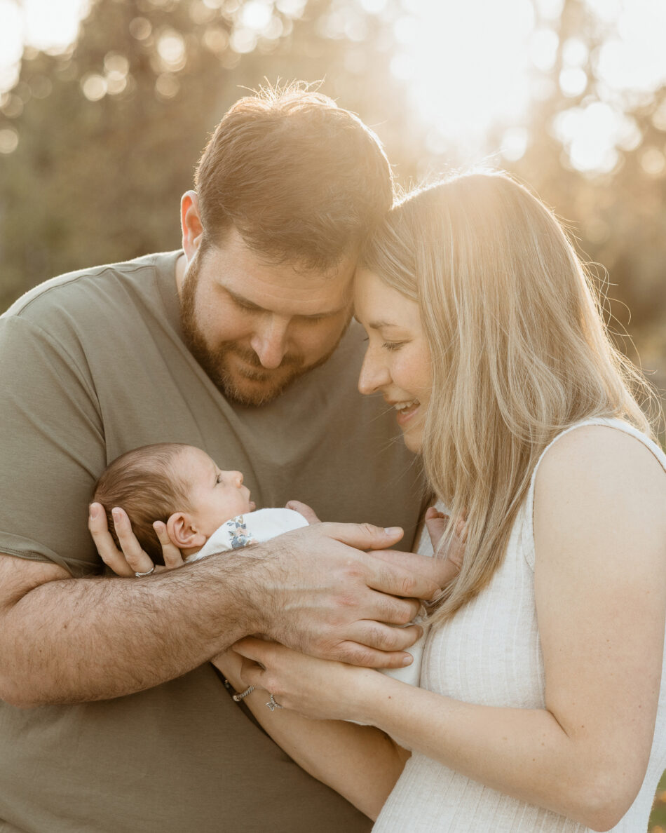 Parents holding their newborn baby during a golden hour outdoor newborn photography session in Calabasas photographed by Erica Montgomery.