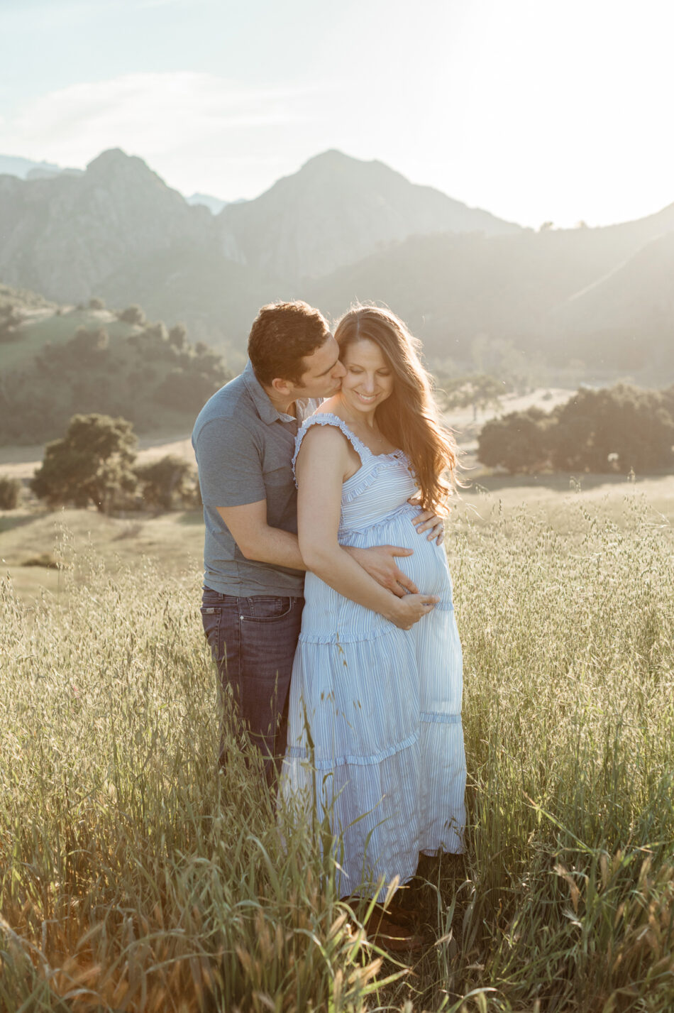 Couple embracing during a golden hour maternity photography session in the hills of Malibu photographed by Erica Montgomery.