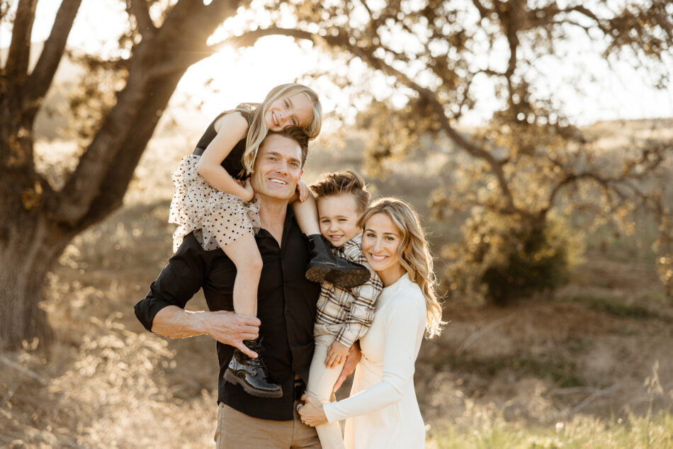 Family of four smiling together during a golden hour family photography session at Malibu Creek State Park photographed by Erica Montgomery.
