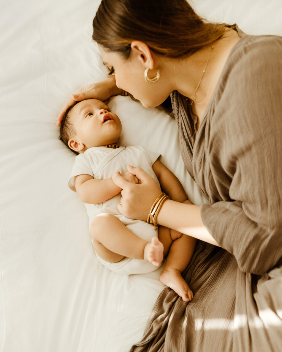 Mother looking down at her newborn baby during a natural light in-home newborn photography session in West Hills photographed by Erica Montgomery.