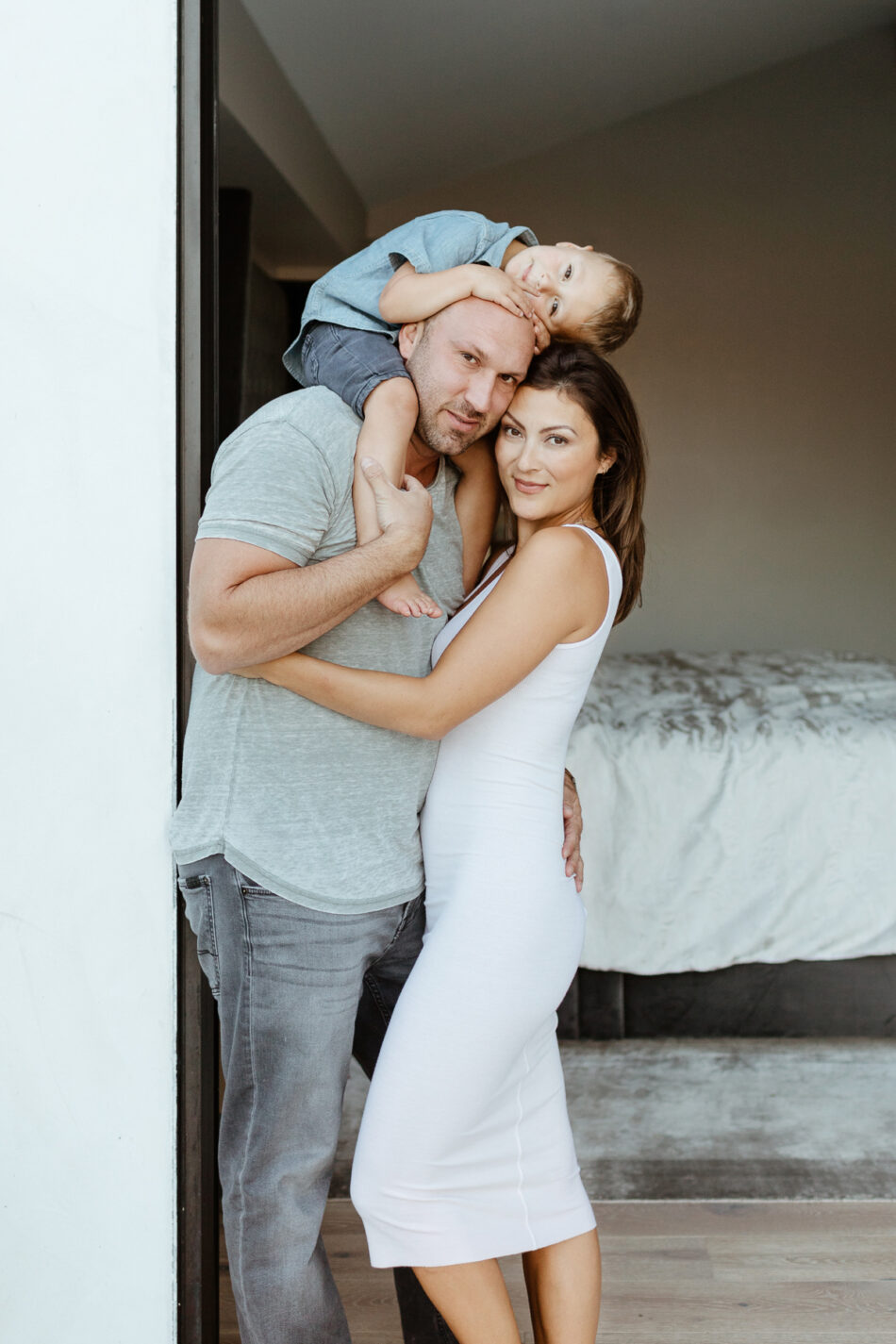 Parents posing by a modern sliding glass door during an in-home lifestyle family photoshoot in Woodland Hills by Erica Montgomery Photography.