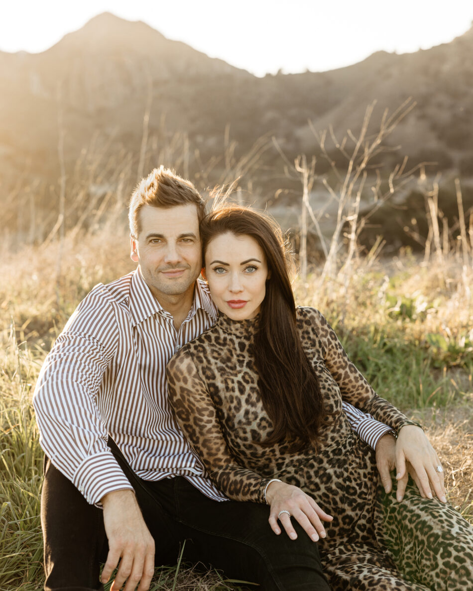 Cinematic couples portrait of a man and woman sitting in a sunlit field in Calabasas by Erica Montgomery Photography.