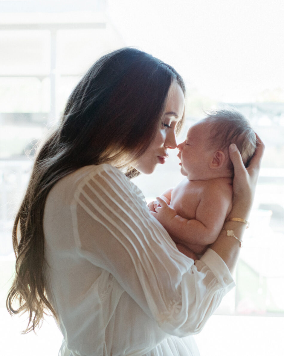 Mother gently holding her newborn baby nose-to-nose by a bright window during an Agoura Hills lifestyle home photoshoot by Erica Montgomery Photography.
