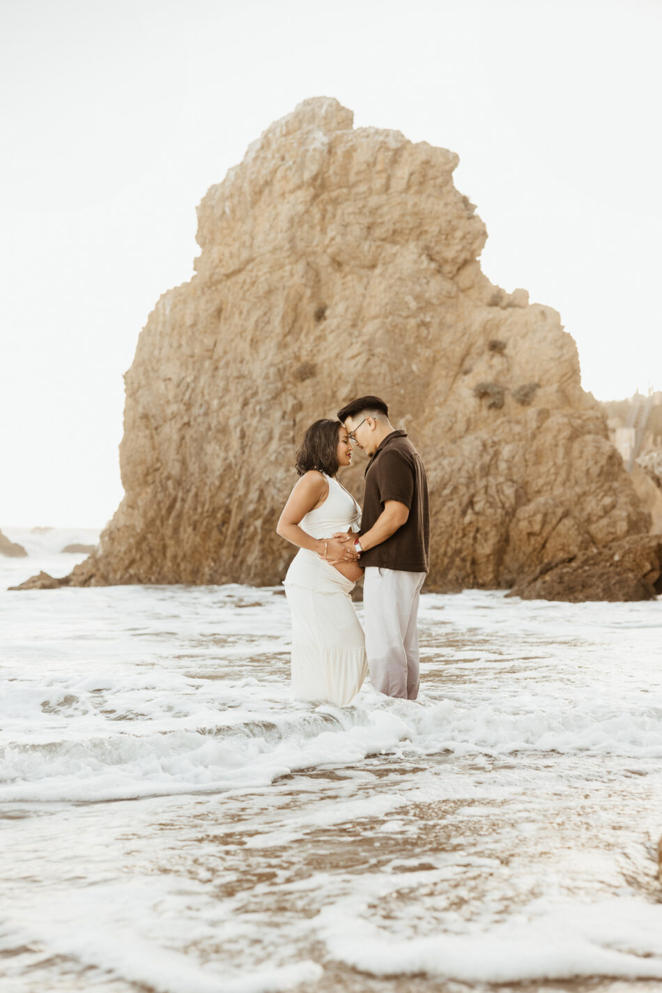Coastal beach maternity photography standing in the ocean surf by the iconic rock formations at El Matador State Beach in Malibu, by Erica Montgomery.
