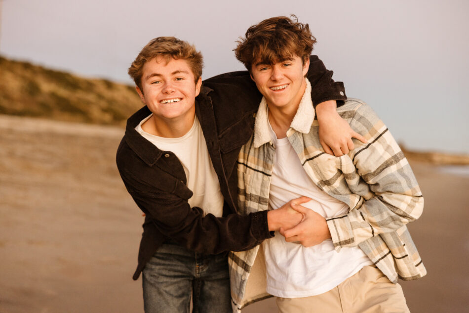 Teenage brothers hugging and laughing on the shoreline during a Malibu beach family photoshoot by Erica Montgomery Photography.