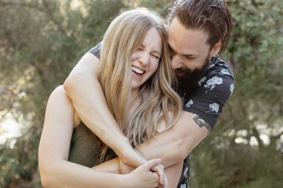 Candid close-up of a blonde woman laughing while hugging her partner during a relaxed couples photoshoot by Erica Montgomery Photography.
