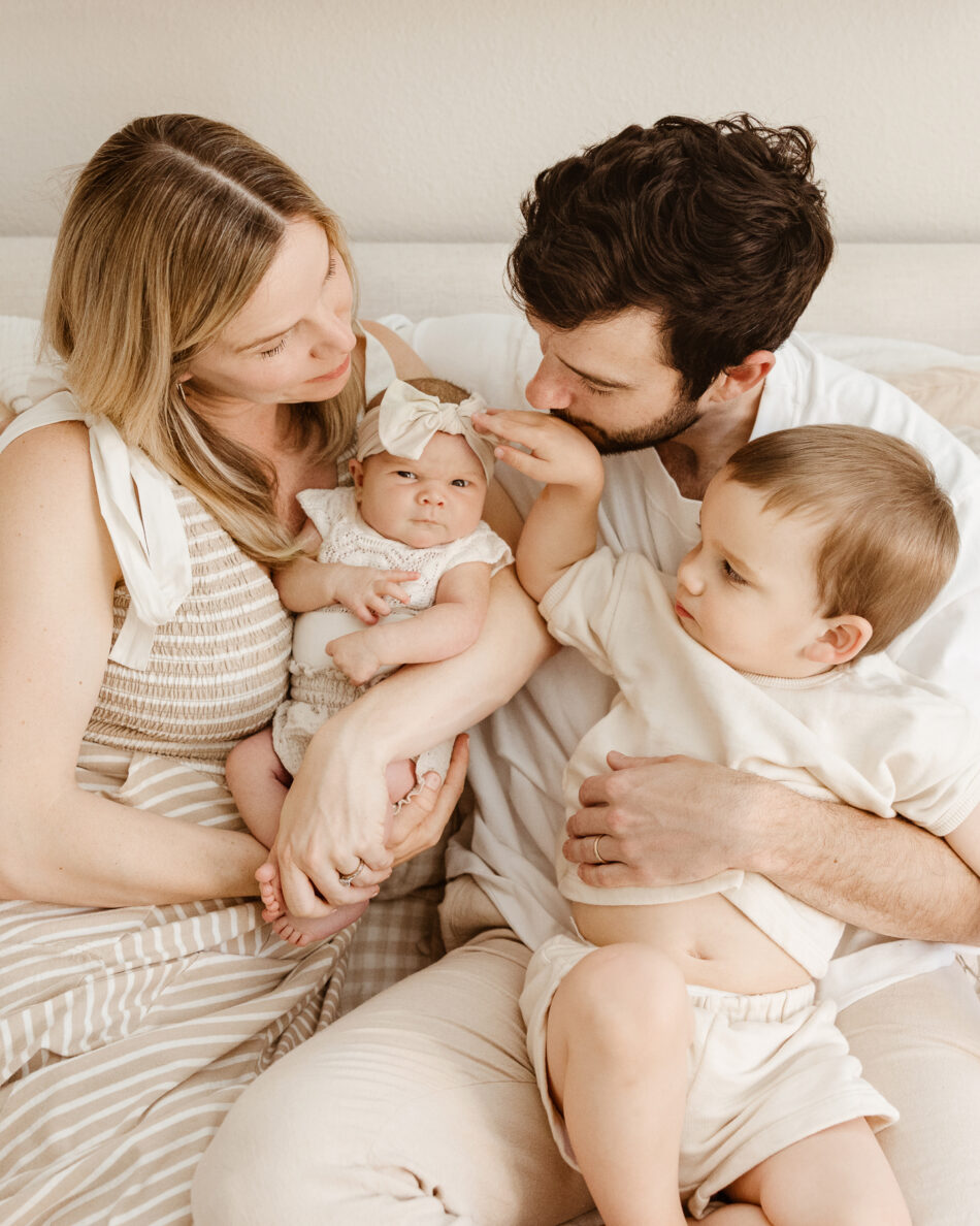 Family of four with a toddler and newborn baby snuggling together during an in-home lifestyle portrait session in Calabasas by Erica Montgomery Photography.
