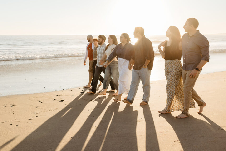 Editorial golden hour photography of an extended family walking along the Malibu shoreline with long, dramatic shadows.
