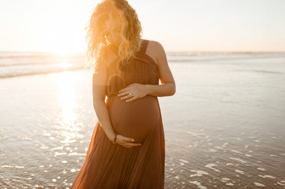 Sunset beach baby bump portraits featuring a golden hour lens flare at Leo Carrillo State Beach in Malibu, by Erica Montgomery.