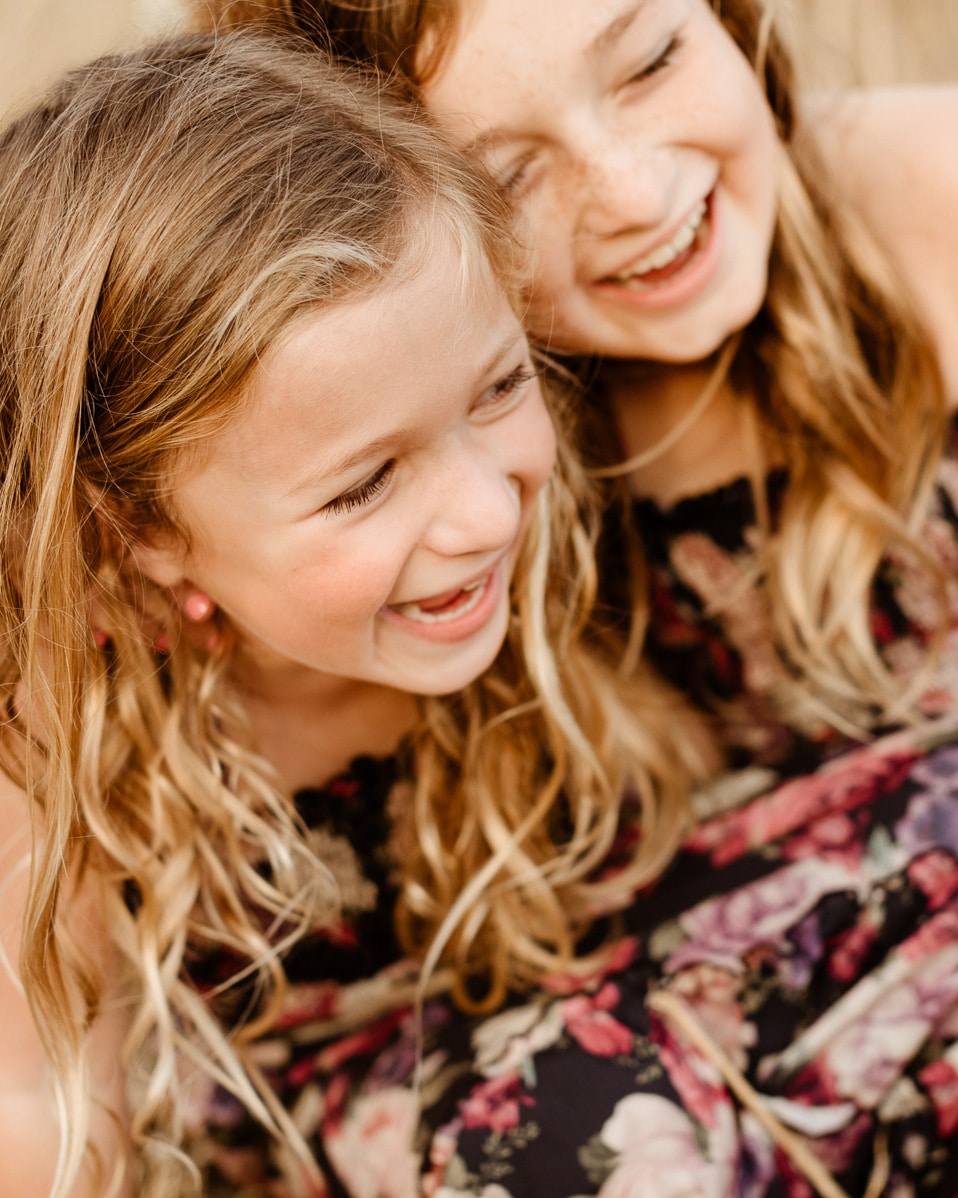 Two sisters laughing together in golden field during Calabasas family photography session